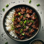 A top-down view of a One-Pot Korean Beef Bowl featuring tender beef in a glossy soy glaze, garnished with green onions and sesame seeds over white rice.