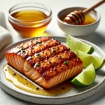 Close-up of gluten-free spicy honey lime grilled salmon with a caramelized crust, garnished with lime wedges on a white plate.